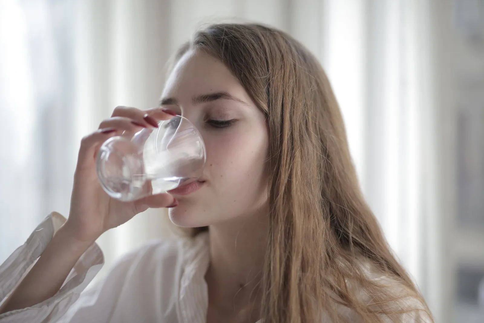 Woman drinking a glass of water; illustrative wellness photograph