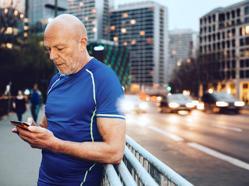 older man on a sidewalk using his phone