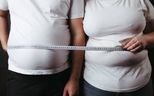 overweight couple measuring waist size