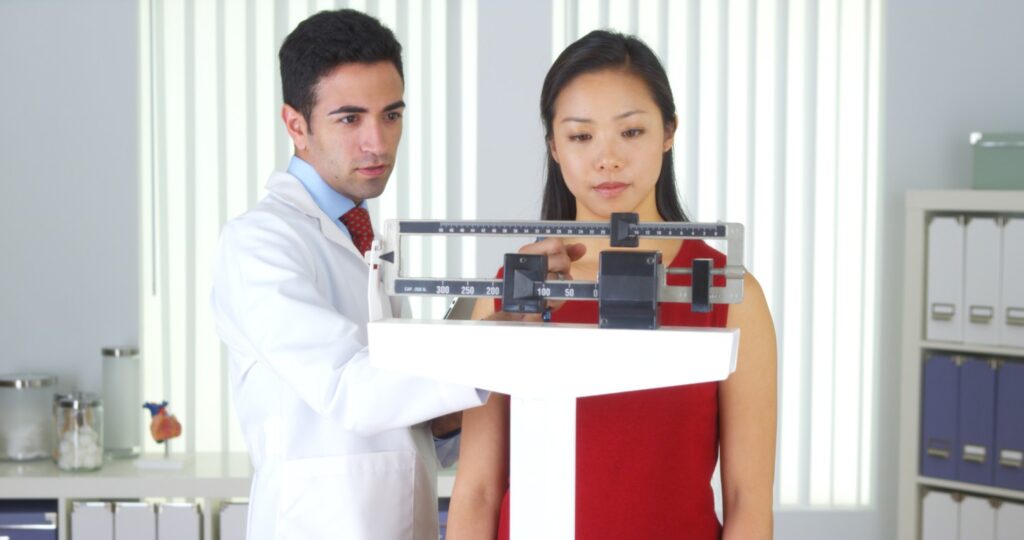doctor with a patient measuring their weight